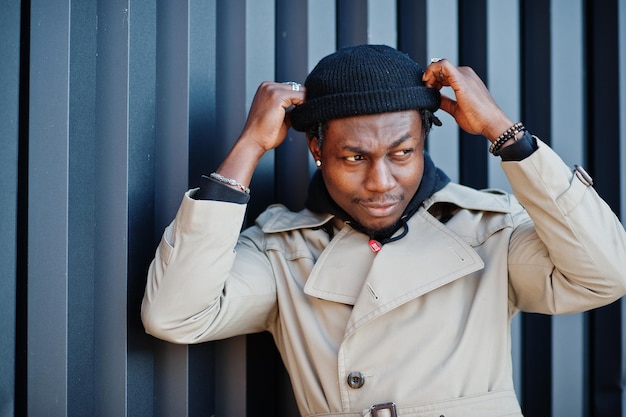 Free photo handsome african american man posing outside in black hat and beige coat