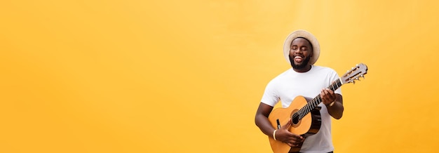 Free Photo handsome african american retro styled guitarist playing acoustic guitar isolated on yellow backgrou