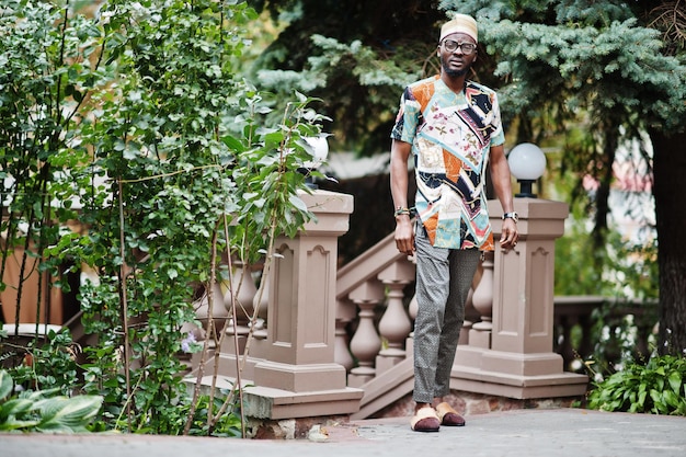 Handsome afro american man wearing traditional clothes cap and eyeglasses in modern city