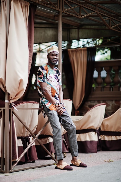 Handsome afro american man wearing traditional clothes and cap in modern city