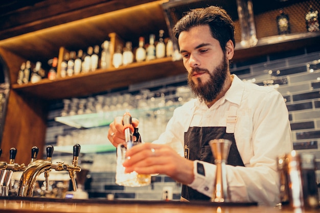 Handsome bartender making drinking and cocktails at a counter