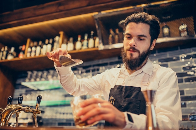 Handsome bartender making drinking and cocktails at a counter