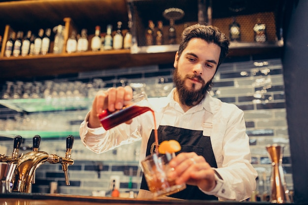 Handsome bartender making drinking and cocktails at a counter