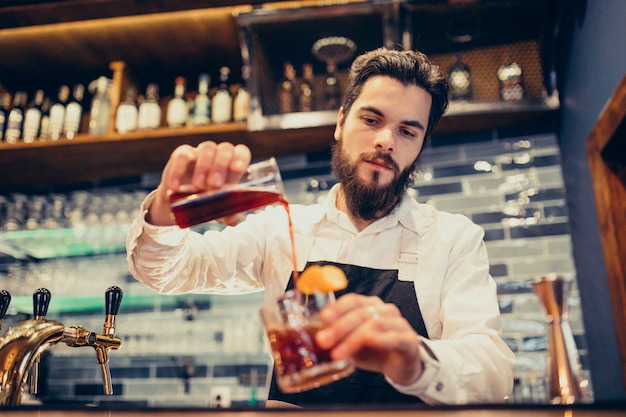 Handsome bartender making drinking and cocktails at a counter