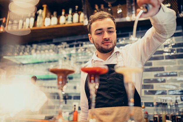 Handsome bartender making drinking and cocktails at a counter