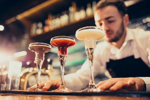 Handsome bartender making drinking and cocktails at a counter