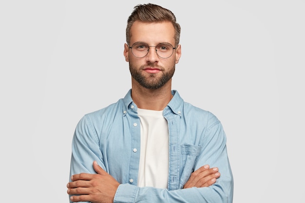 handsome bearded guy posing against the white wall