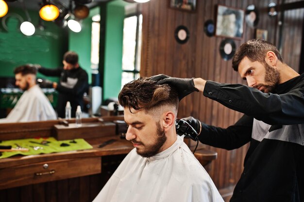 Handsome bearded man at the barbershop barber at work