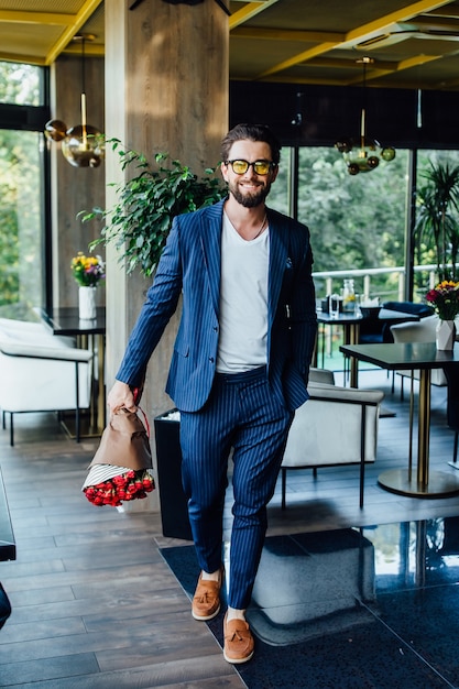 Free photo handsome bearded man with bouquet red roses coming in restaurant