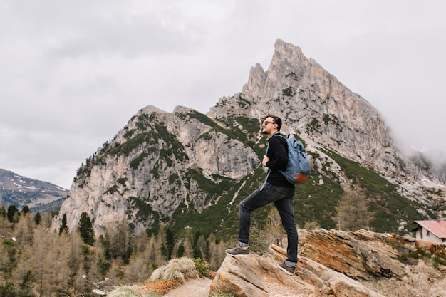 Handsome brunette man stands on the rock admiringly looking at amazing nature views