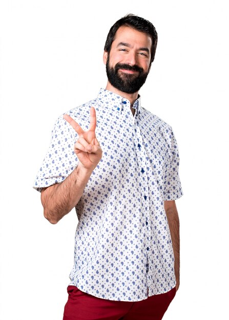 Handsome brunette man with beard making victory gesture