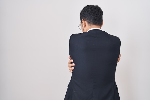 Free photo handsome business hispanic man standing over white background hugging oneself happy and positive from backwards. self love and self care