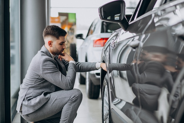 Handsome business man choosing a car in a car showroom