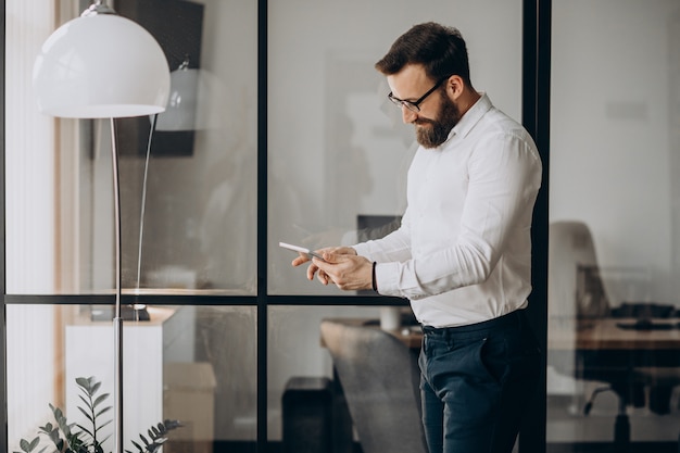 Handsome business man stnading in pffice and holding tablet