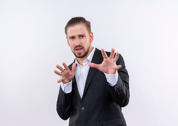 Free photo handsome business man wearing suit holding arms out with disgusted expression standing over white background