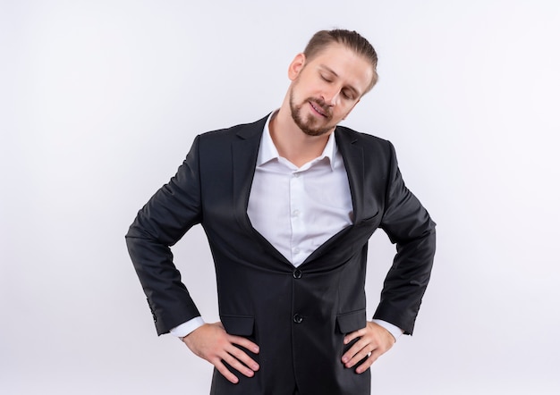 Handsome business man wearing suit looking aside with confident expression standing over white background