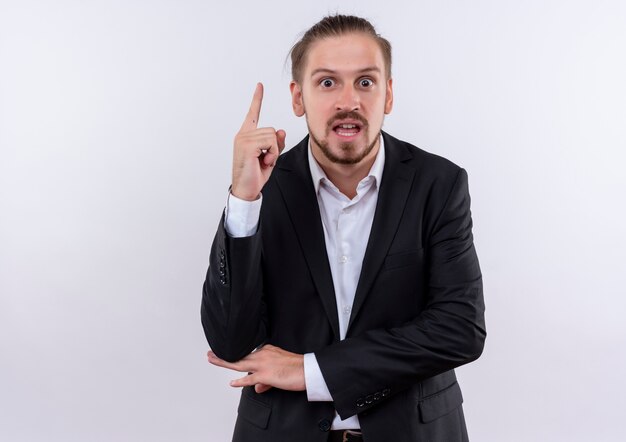 Handsome business man wearing suit showing index finger looking surprised having great new idea standing over white background