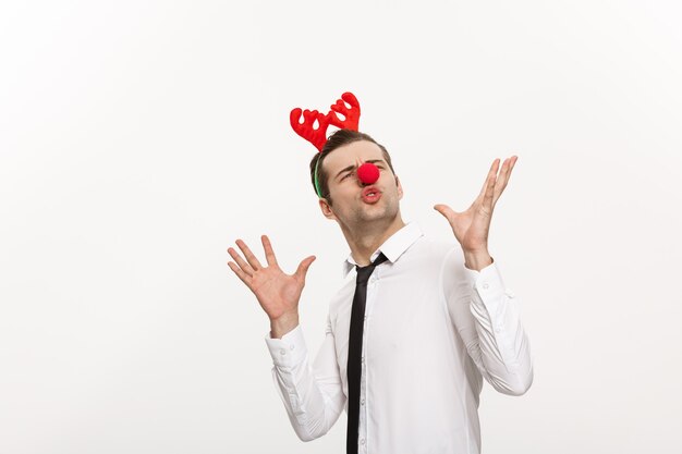 Free photo handsome business man wearinging reindeer hairband making funny facial expression isolated on white.