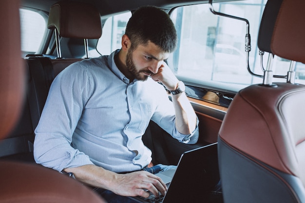 Free photo handsome business man working on a computer in car