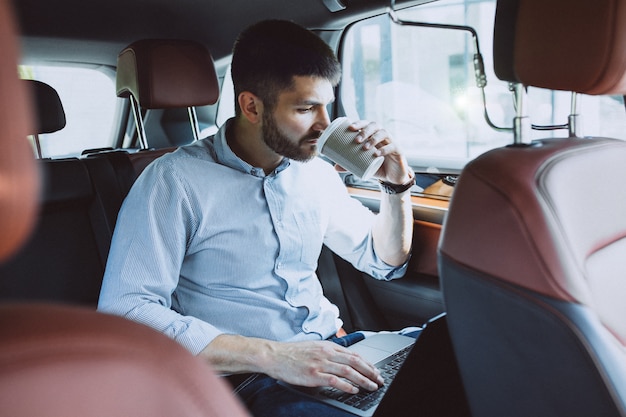 Free Photo handsome business man working on a computer in car