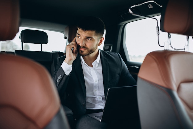 Free photo handsome business man working on a computer in car