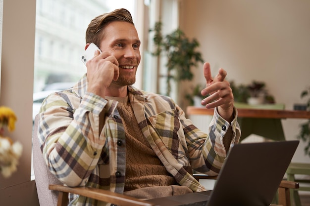 Free photo handsome businessman in coffee shop sitting in cafe with laptop and calling someone man talking on