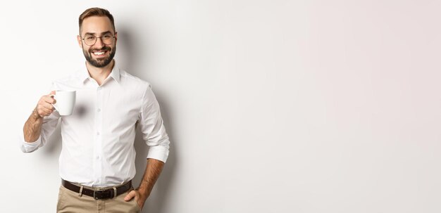 Handsome businessman drinking coffee and smiling standing against white background