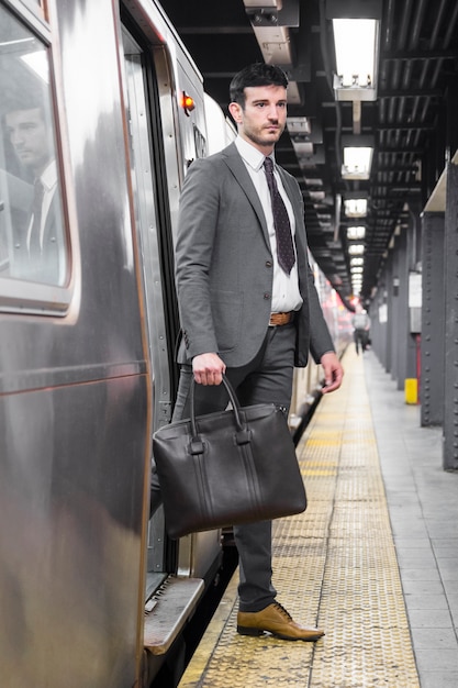 Free photo handsome businessman exiting subway car