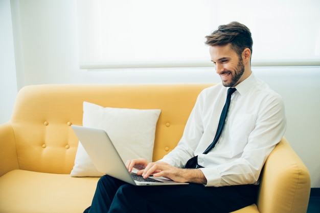 Free photo handsome businessman laughing and working with his laptop