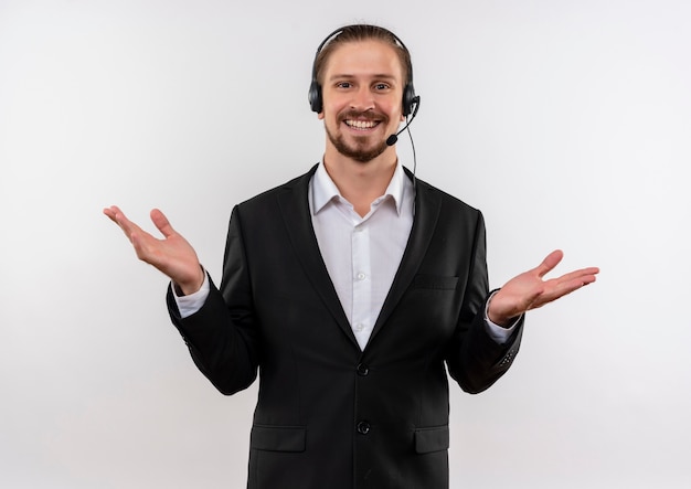 Free Photo handsome businessman in suit and headphones with a microphone looking at camera happy and positive smiling cheerfully standing over white background