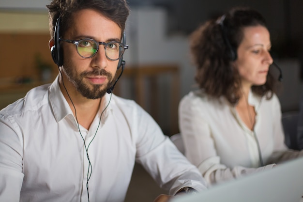 Free photo handsome call center operator in eyeglasses looking at camera