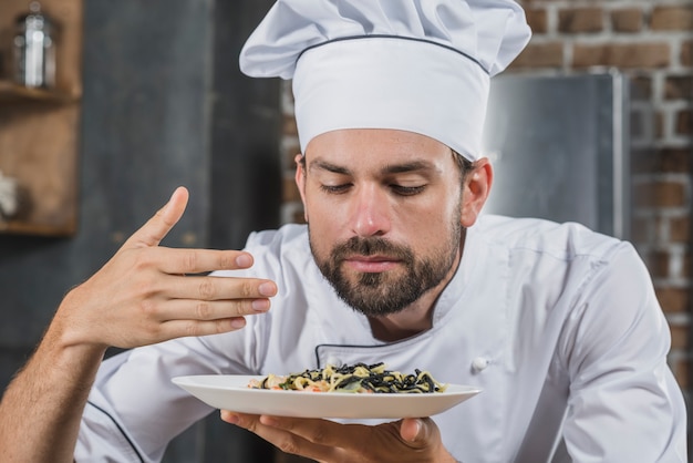 Free photo handsome chef sniffing smell of cooked dish