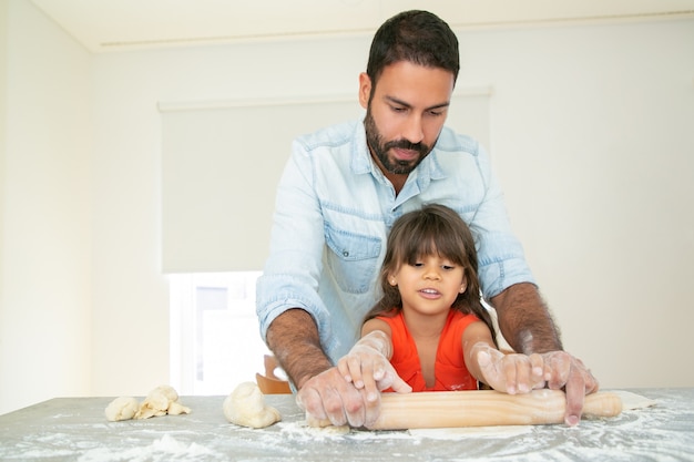 Handsome dad teaching daughter to bake.