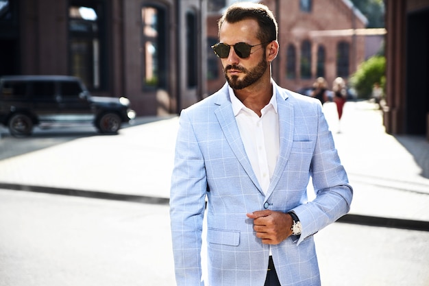 handsome fashion businessman model dressed in elegant blue suit posing on street