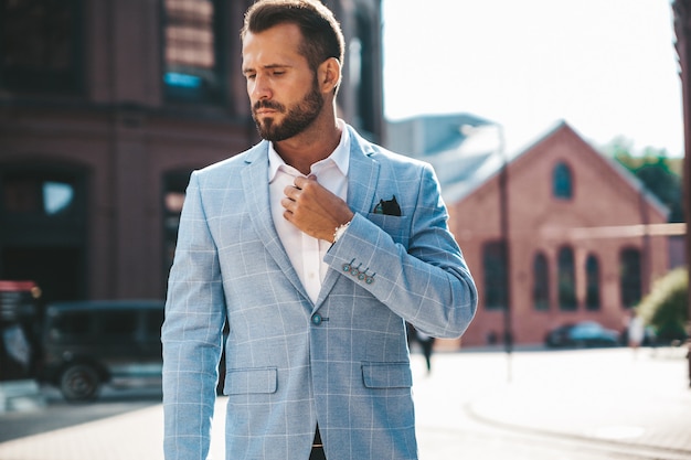 handsome fashion businessman model dressed in elegant blue suit posing on street