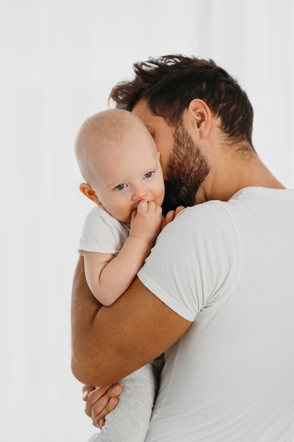 Handsome father holding and kissing his baby