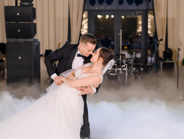 Free photo handsome groom holding bride while dancing wedding dance