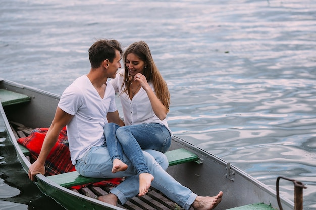 Free photo handsome guy and beautiful girl resting in a boat on the lake