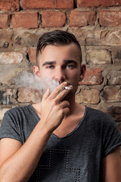 Handsome guy smoking near the wall