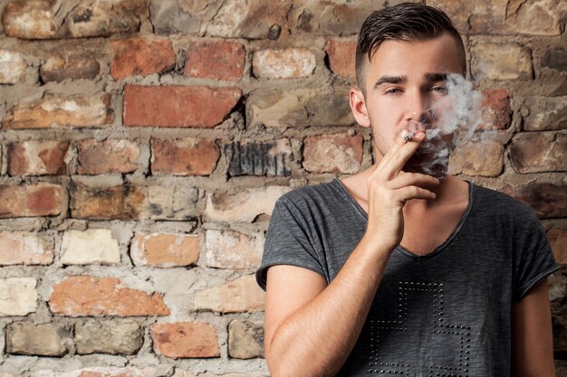 Handsome guy smoking near the wall