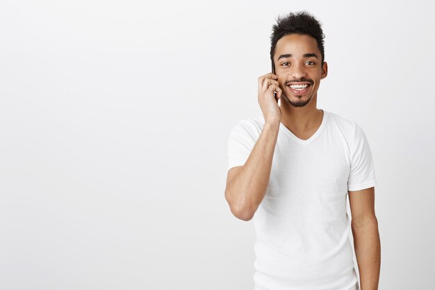 Handsome happy Black man smiling and talking on mobile phone