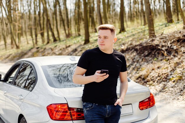 Free photo handsome, happy, young man uses smartphone in car and outdoors