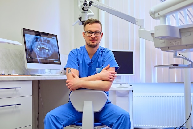 Handsome male dentist in a room with medical equipment on background.