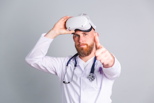 Free photo handsome male doctor on gray wall in virtual reality glasses