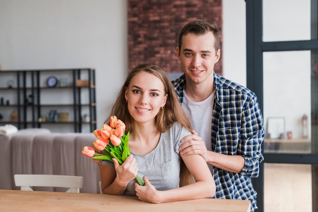 Handsome male hugging wife with beautiful flowers