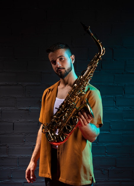 Free photo handsome male musician holding saxophone