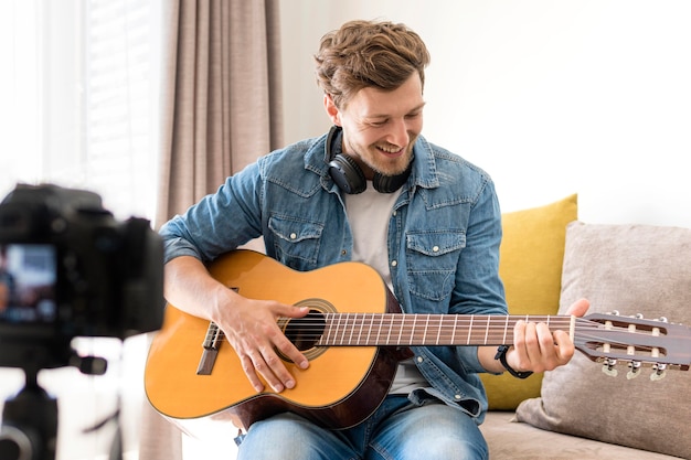 Handsome male recording guitar session at home