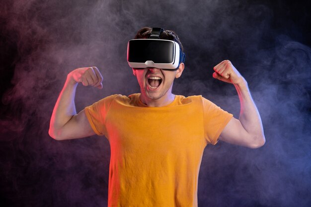 Handsome male wearing virtual reality headset on dark surface