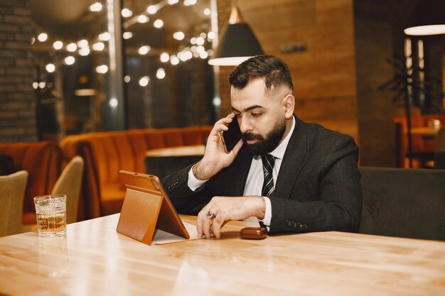 Handsome man in a black suit, working in a cafe