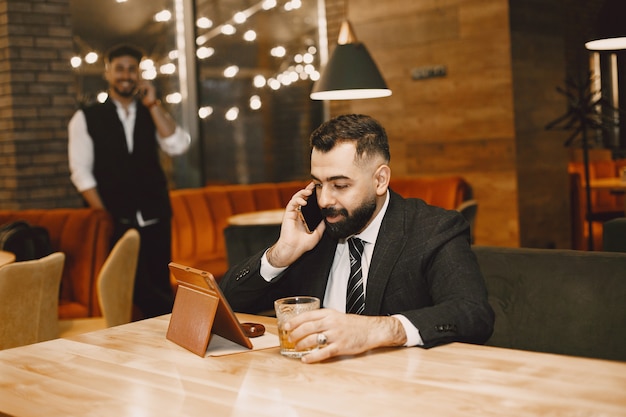 Handsome man in a black suit, working in a cafe